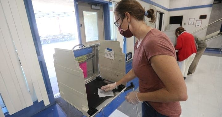 A California poll worker sanitizes a voting booth following its use at a Voter Assistance Center during the 2020 General Election.
